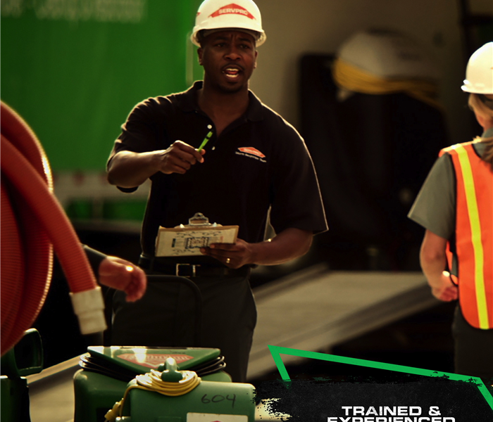 SERVPRO crew wearing protective head gear standing in front of equipment with caption: TRAINED & EXPERIENCED PROFESSIONALS